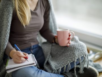 Young woman sitting on the floor and writting notes
