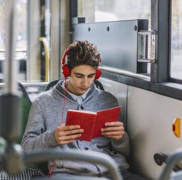 A teenage boy with headphones on, travelling on the bus.