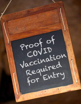 (alt="Proof of COVID vaccination required for entry signage")
